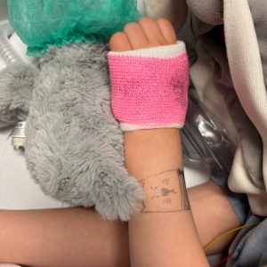 Foto van de patiënt haar roze gips met glitter en de kattekening op haar arm - Sophia kinderziekenhuis